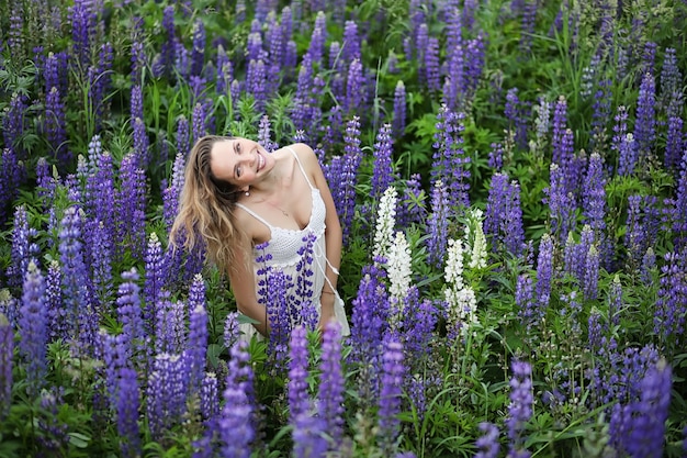 Belle fille avec un bouquet de fleurs bleues sur la nature en été