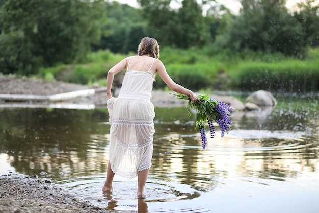 Belle fille avec un bouquet de fleurs bleues sur la nature en été