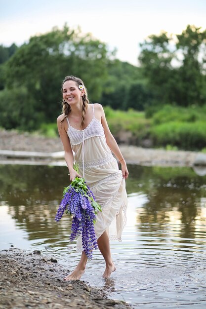 Belle fille avec un bouquet de fleurs bleues sur la nature en été