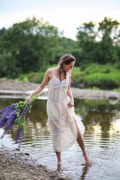 Belle fille avec un bouquet de fleurs bleues sur la nature en été