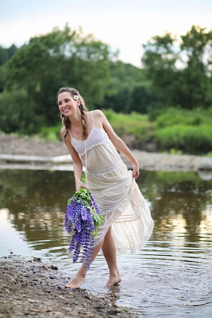 Belle fille avec un bouquet de fleurs bleues sur la nature en été