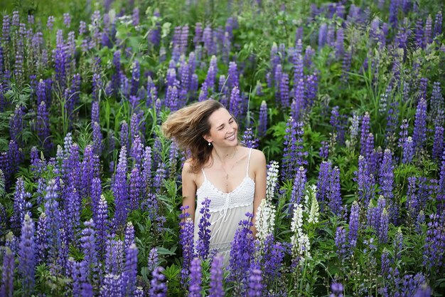 Belle fille avec un bouquet de fleurs bleues sur la nature en été