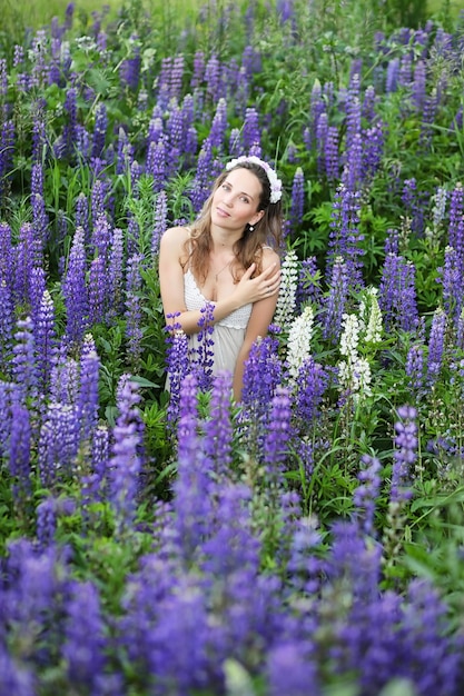 Une belle fille avec un bouquet de fleurs bleues sur la nature en été