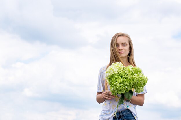 Belle fille avec un bouquet sur le fond du ciel