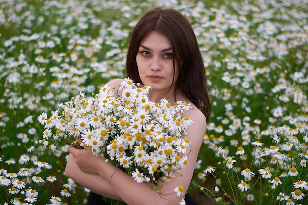 Belle fille avec un bouquet de marguerites dans un champ de fleurs.