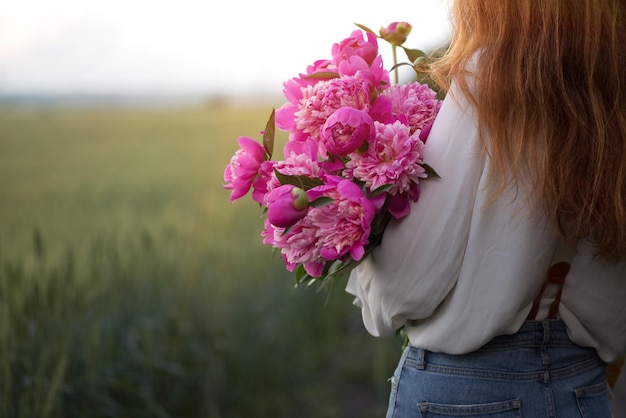 Belle fille avec un bouquet de pivoine