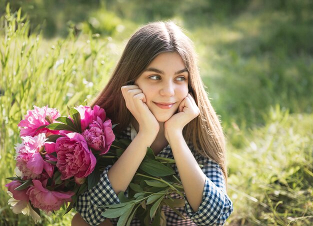 Belle fille avec un bouquet de pivoines