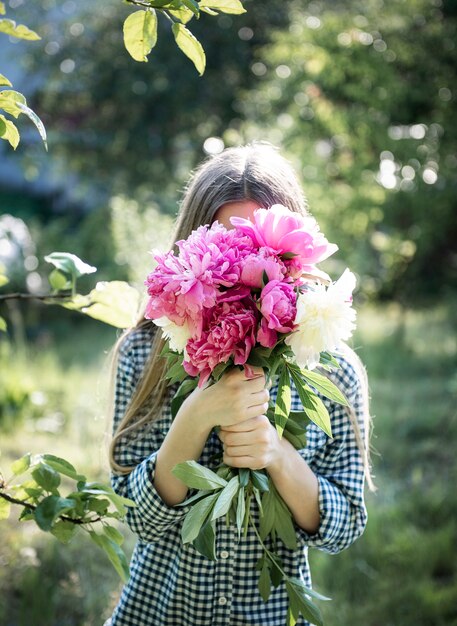 Belle fille avec bouquet de pivoines