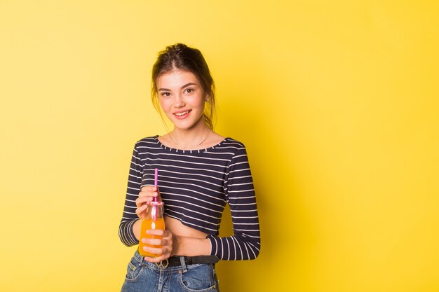 Belle fille avec une bouteille de jus de fruits frais