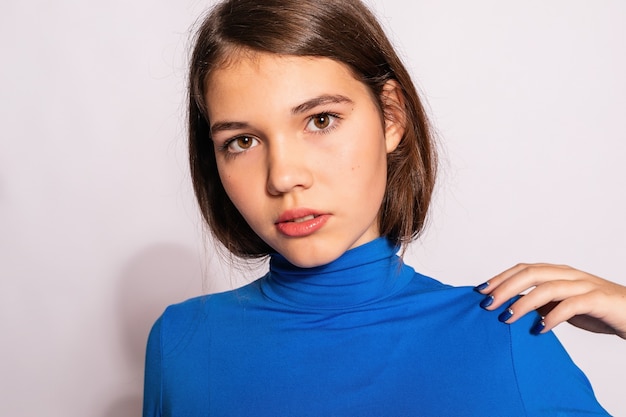 Belle fille branchée de hipster. Photo d'une belle jeune femme positive en chaussettes hautes bleues avec fond blanc. regarde la caméra