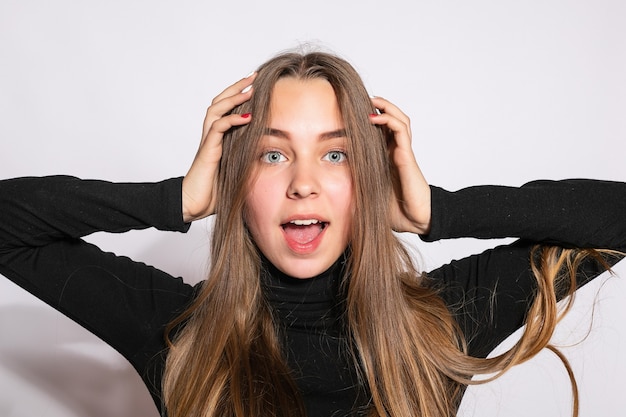 Belle fille branchée de hipster. Photo d'une belle jeune femme positive dans des chaussettes hautes noires avec un fond blanc. regarde la caméra. surpris avec sa main et lève les yeux