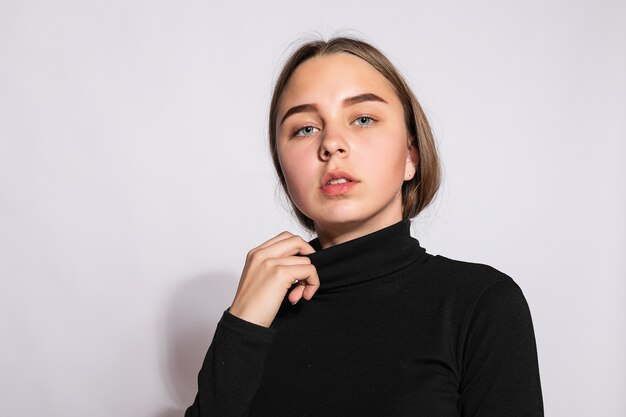 Belle fille branchée de hipster. Photo d'une belle jeune femme positive dans des chaussettes hautes noires avec un fond blanc. regarde la caméra.