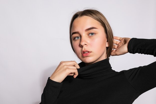 Belle fille branchée de hipster. Photo d'une belle jeune femme positive dans des chaussettes hautes noires avec un fond blanc. regarde la caméra.