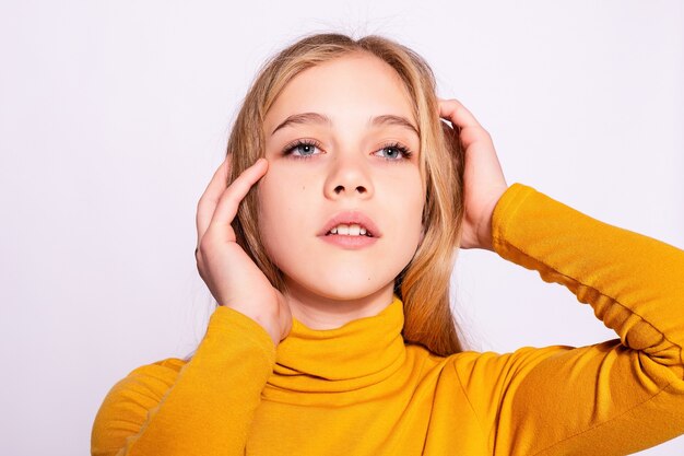 Belle fille branchée de hipster. Photo d'une belle jeune femme positive en jaune jusqu'aux genoux avec un fond blanc. rêver