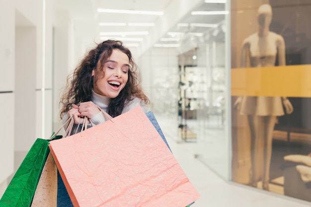 Belle fille brune, aux cheveux bouclés, choisit des vêtements dans une boutique