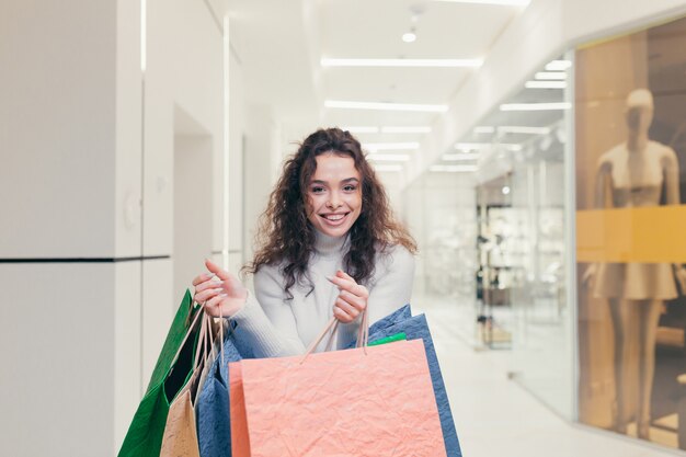 Belle fille brune, aux cheveux bouclés, choisit des vêtements dans une boutique