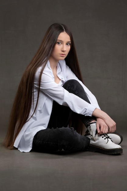 Belle fille brune aux cheveux très longs sur fond gris.