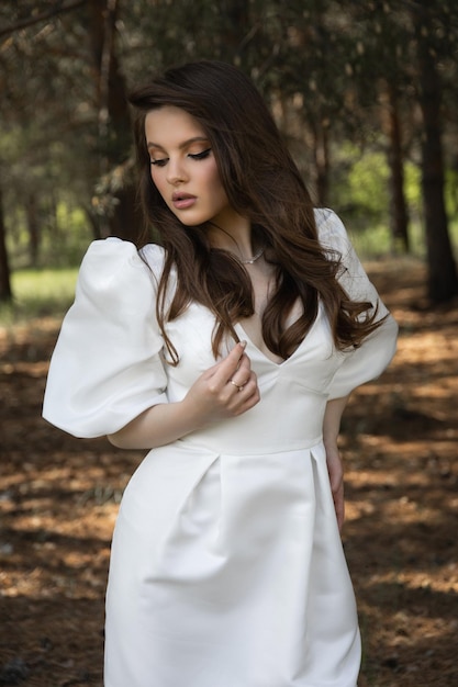 Photo belle fille brune caucasienne dans une robe de mariée dans la forêt