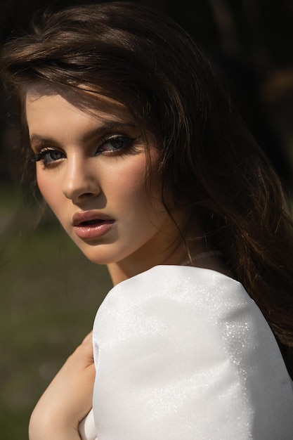 Photo belle fille brune caucasienne dans une robe de mariée regarde la caméra beau look