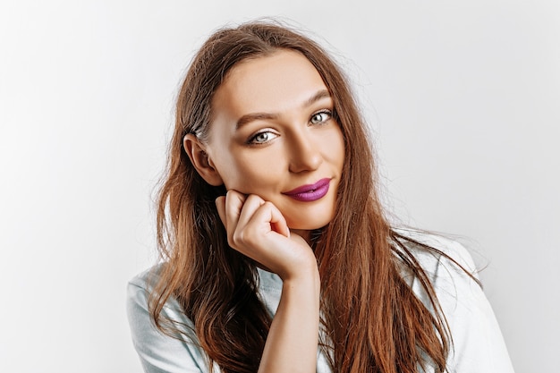 Belle fille brune douce sur un mur gris isolé