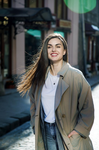 Belle fille brune marchant dans la rue ensoleillée du printemps