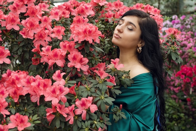 Belle fille brune parmi un jardin fleuri, une fille parmi les fleurs. Photo de haute qualité