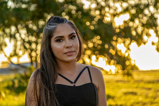 Belle fille brune posant sur des photos dans la nature au coucher du soleil.