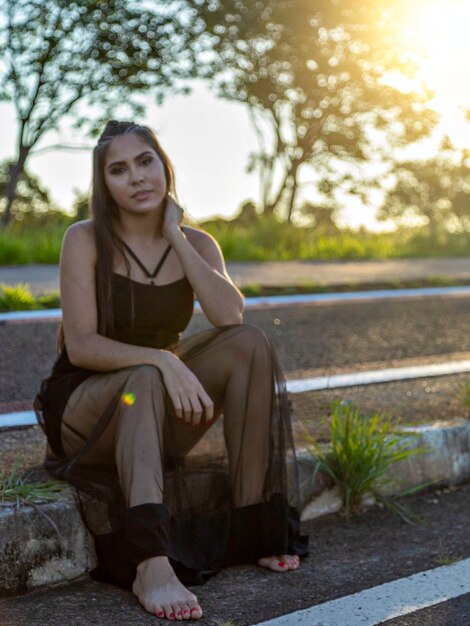 Belle fille brune posant sur des photos dans la nature au coucher du soleil.