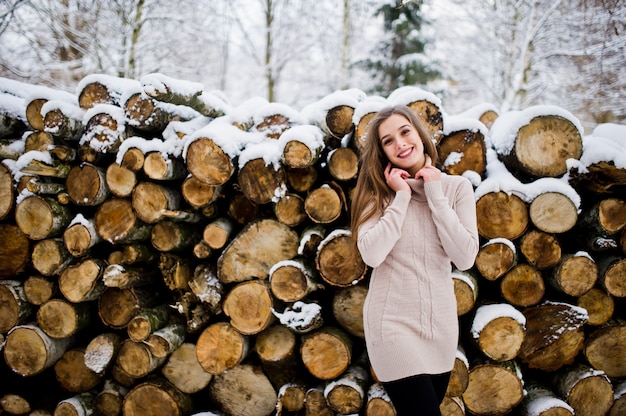 Belle fille brune en vêtements chauds d'hiver. Modèle sur pull d'hiver près de souche.