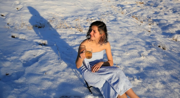 Belle fille buvant du thé sur la neige en hiver