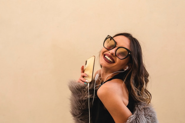 Belle fille avec un casque écoute de la musique et des danses à l'extérieur. Fond de mur blanc