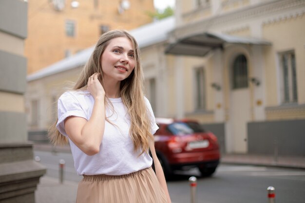 Belle fille caucasienne aux cheveux blonds regarde de côté dans la ville dans le contexte d'une voiture