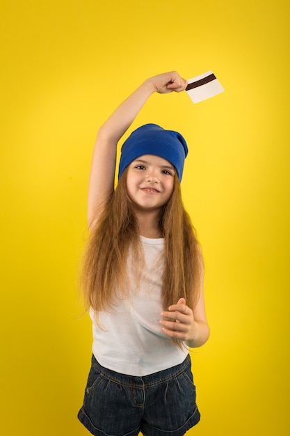 Belle fille caucasienne posant tenant en mains une carte de crédit