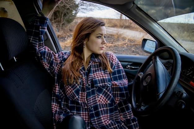 Belle fille en chemise dans la voiture