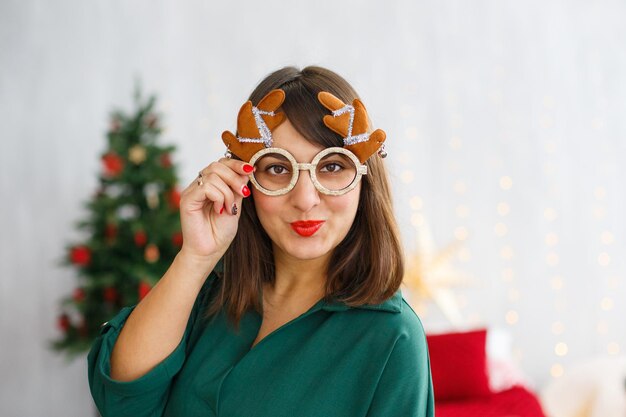 Belle fille en chemise verte et lunettes de Noël avec des cornes de cerf Décoration de nouvel an