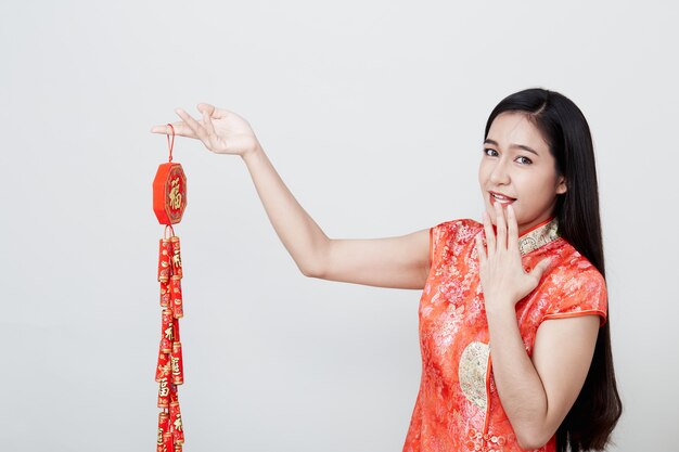 Belle fille en cheongsam rouge tenant des pétards