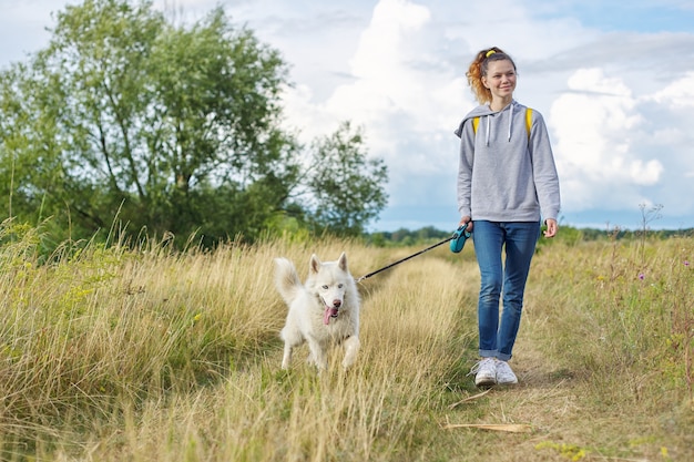 Belle fille avec un chien blanc qui marche