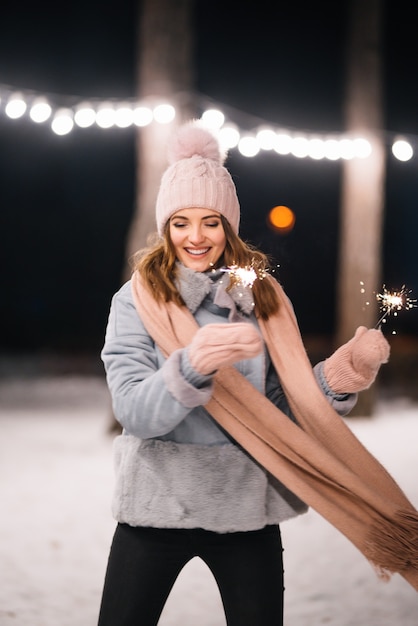 Belle fille avec des cierges magiques dans les mains Joyeux hiver dans la forêt Guirlande lumineuse festive