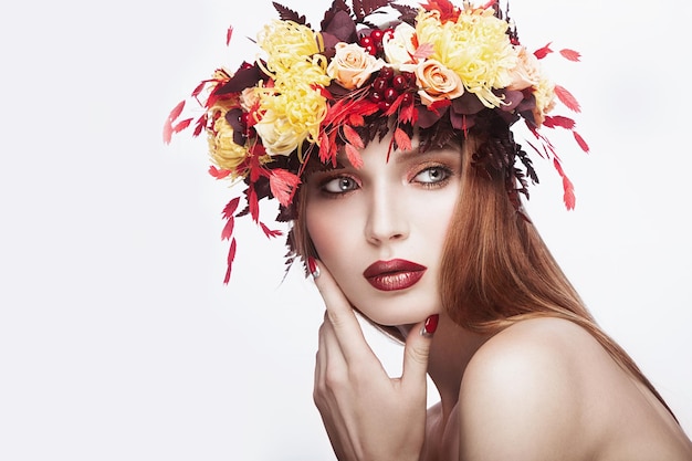 Belle fille avec une couronne d'automne lumineuse de feuilles et de fleurs Visage de beauté