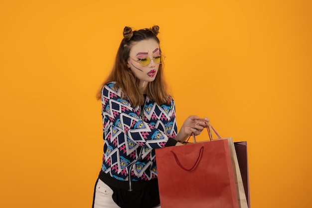 Belle fille créative tenant des sacs à provisions et regardant à l'intérieur du sac. Photo de haute qualité