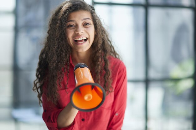 Belle fille criant dans un mégaphone dans un bureau moderne