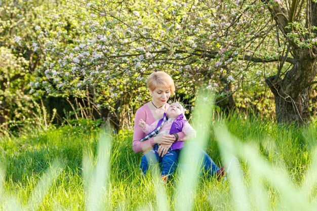 Une belle fille dans les bras d'une enfant dans un parc en fleurs