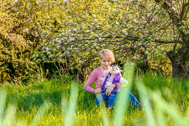 Belle fille dans les bras d'une petite fille dans un parc fleuri en gros plan