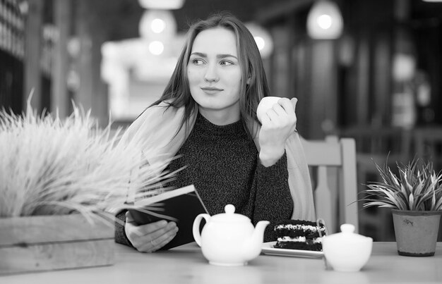 Belle fille dans un café assis et buvant du thé avec un dessert