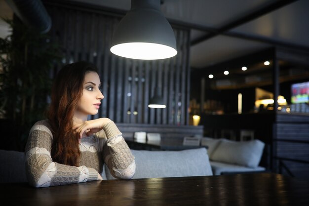 Belle fille dans un café prenant une tasse de café lors d'un dîner