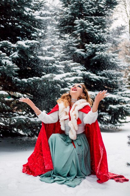 Belle fille dans une cape rouge dans la forêt d'hiver