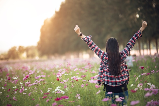 Belle Fille Dans Un Champ De Fleurs De Cosmos Au Coucher Du Soleil. Concept De Liberté