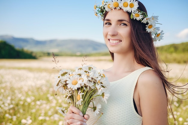 Belle fille dans un champ de marguerites Coucher de soleil d'été heureuse jeune femme et concept d'harmonie de la nature printanière Femme brune heureuse insouciante avec des cheveux ondulés en bonne santé s'amusant en plein air dans la nature