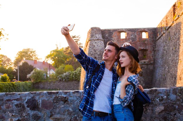 La belle fille dans un chapeau élégant, avec le petit ami fait un selfie dans le contexte d'une forteresse