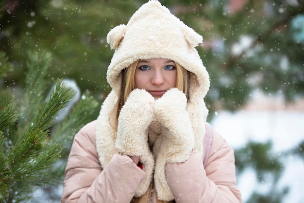 Belle fille dans un chapeau de fourrure et des mitaines sur un fond d'hiver